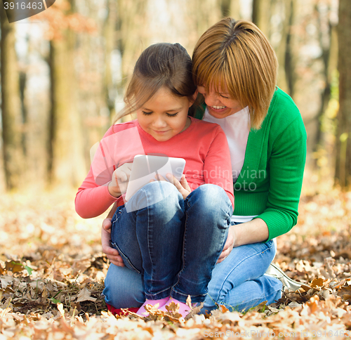 Image of Mother is reading from tablet with her daughter