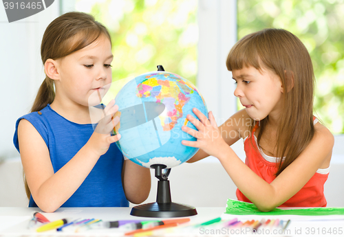 Image of Little girls are examining globe