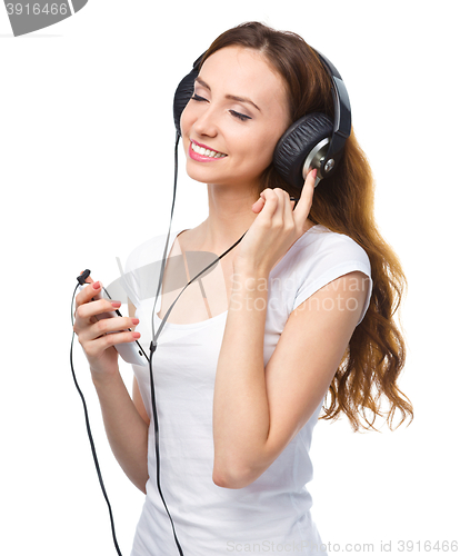 Image of Young woman enjoying music using headphones