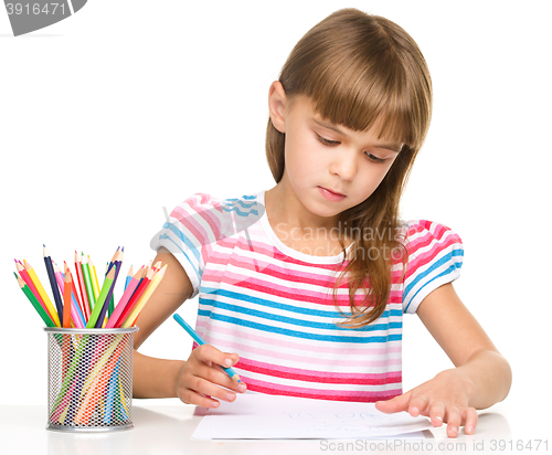 Image of Little girl is drawing using pencils