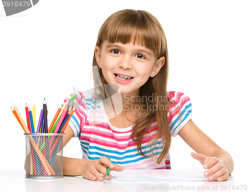 Image of Little girl is drawing using pencils