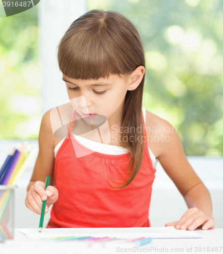 Image of Little girl is drawing using pencils