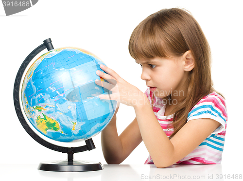 Image of Little girl is examining globe