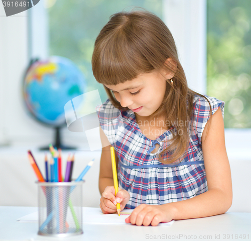 Image of Little girl is drawing using pencils