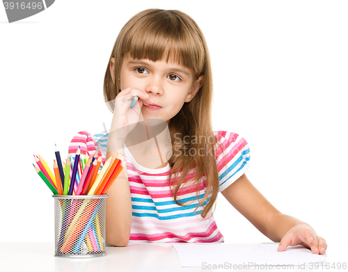 Image of Little girl is drawing using pencils