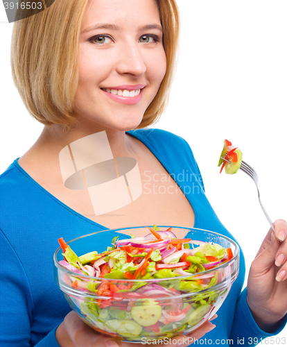 Image of Young attractive woman is eating salad using fork