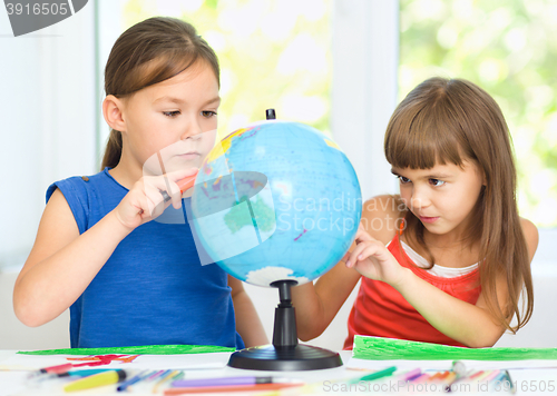 Image of Little girls are examining globe