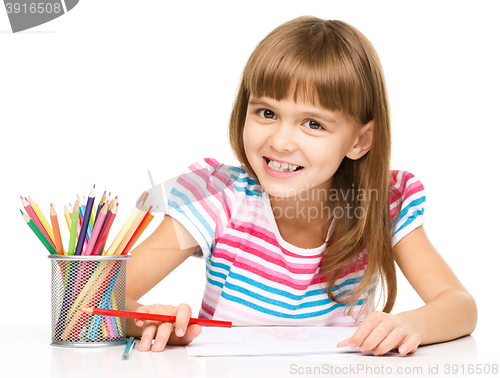 Image of Little girl is drawing using pencils