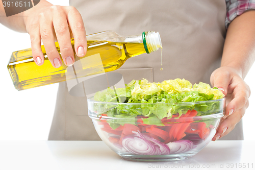 Image of Cook is pouring olive oil into salad