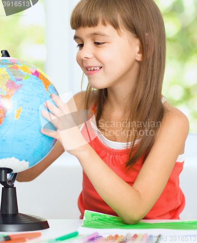 Image of Little girl is examining globe