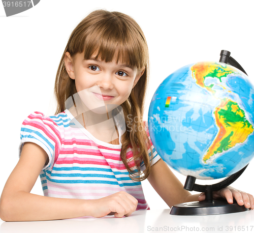 Image of Little girl is examining globe