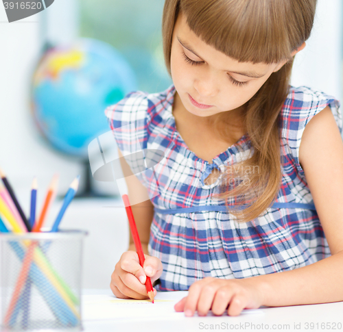 Image of Little girl is drawing using pencils