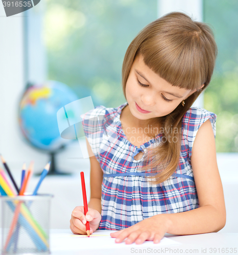 Image of Little girl is drawing using pencils