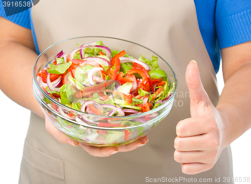 Image of Cook is holding a big bowl with fresh salad