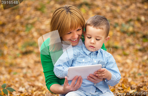 Image of Mother is reading from tablet with her son