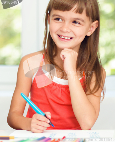 Image of Little girl is drawing using pencils