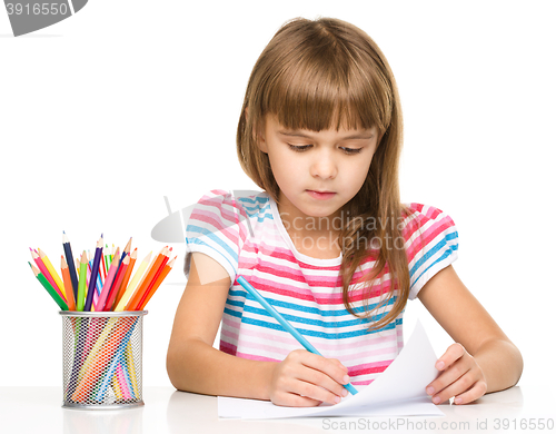 Image of Little girl is drawing using pencils