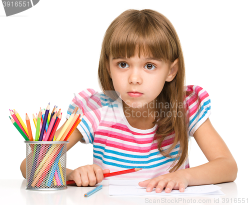 Image of Little girl is drawing using pencils