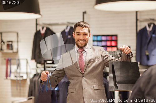 Image of happy man with shopping bags at clothing store