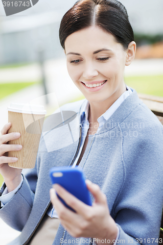 Image of smiling woman with coffee and smartphone