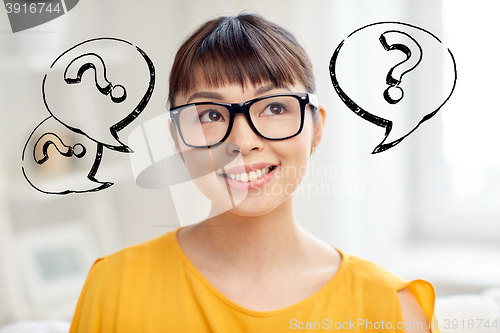 Image of happy asian woman in glasses over question marks