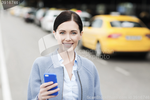 Image of smiling woman with smartphone over taxi in city