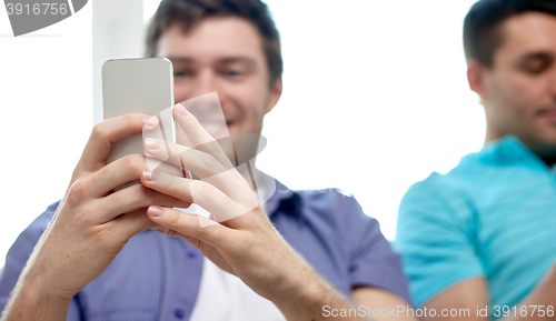 Image of close up of happy friends with smartphones at home