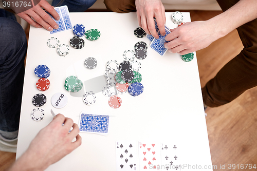 Image of close up of male friends playing cards at home