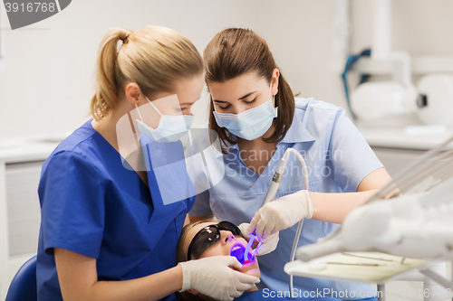 Image of female dentists treating patient girl teeth