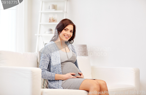 Image of happy pregnant woman sitting on sofa at home