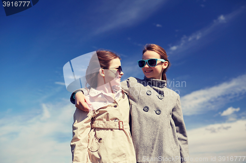 Image of happy little girls hugging and talking outdoors