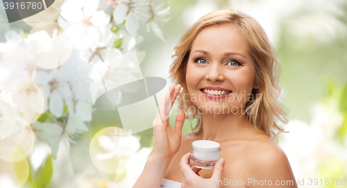 Image of happy woman applying cream to her face