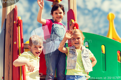 Image of group of happy kids waving hands on playground