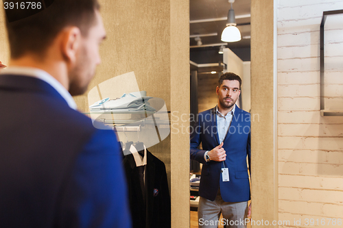 Image of man trying jacket on at mirror in clothing store