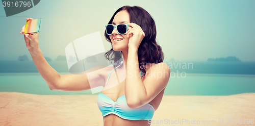 Image of woman in swimsuit taking selfie with smatphone