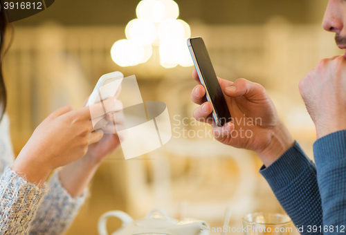 Image of close up of couple with smartphones at cafe