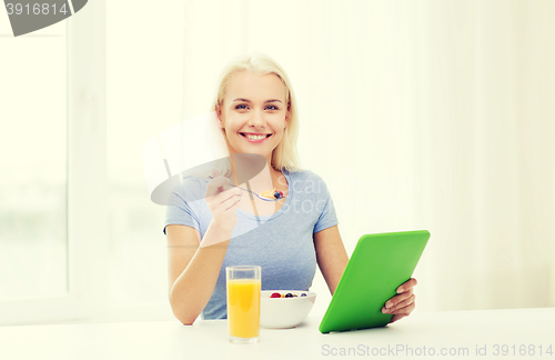 Image of smiling woman with tablet pc eating breakfast