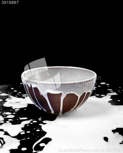 Image of Ceramic bowl and spilled milk in black