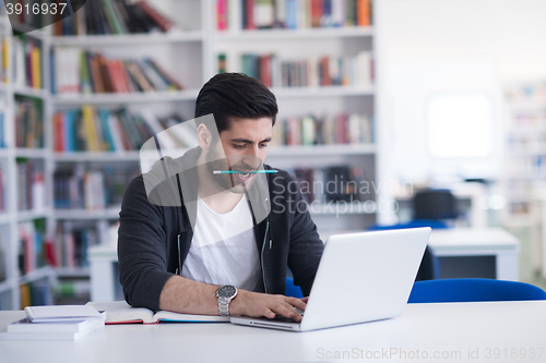 Image of student in school library using laptop for research