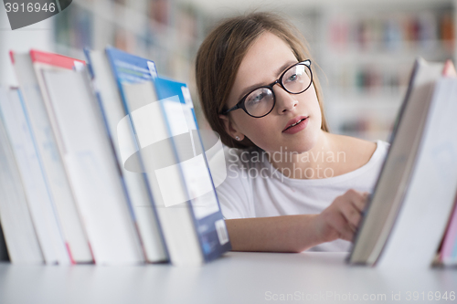 Image of portrait of famale student selecting book to read in library