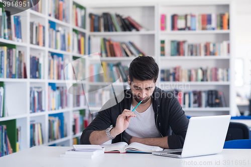 Image of student in school library using laptop for research