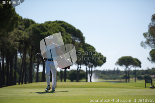 Image of golf player walking and carrying bag