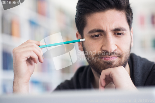 Image of student in school library using laptop for research