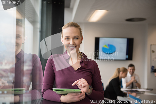 Image of blonde businesswoman working on tablet at office