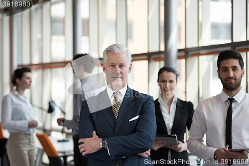 Image of portrait of senior businessman as leader  with group of people i