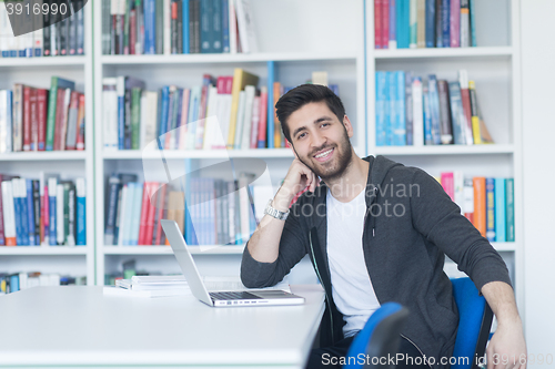 Image of student in school library using laptop for research