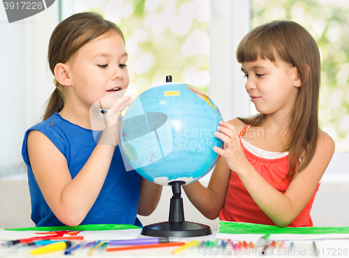 Image of Little girls are examining globe