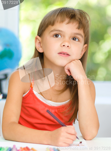 Image of Little girl is drawing using pencils