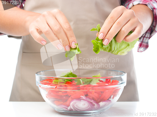 Image of Cook is tearing lettuce while making salad