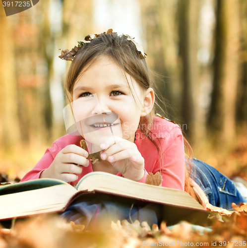 Image of Little girl is reading a book outdoors